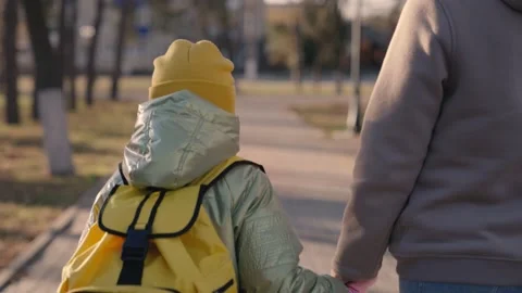Child with a backpack goes to school holding hand of mother in glare of the sun Stock Footage 166019449