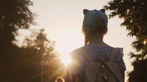 A child with a backpack is standing in the park, the setting sun shines on him Stock-Footage 109176236