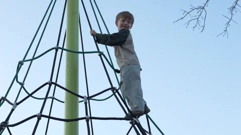Child balancing on rope climbing frame in park illustrating rope activity and Video stock 329277541