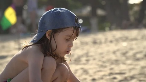 A child in a baseball cap plays on the beach. Stock Footage 119220360