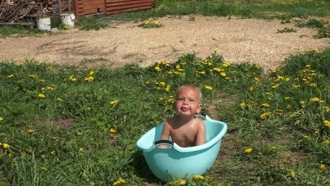 The child bathing in a basin of water.  Sunny day. Stock Footage 85000965