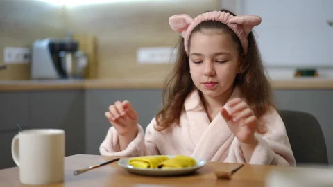 A child in a bathrobe rubs his hands in anticipation of a delicious breakfast Stock Footage 269258317