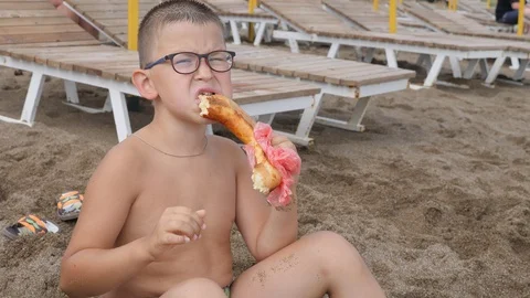 Child on the beach eating cheese bread. Stock Footage 99703627