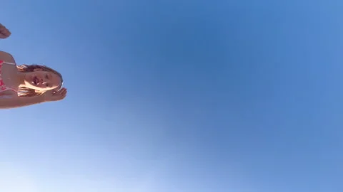 A child on the beach jumps over the camera. View from the bottom of the top to Stock Footage 252768674