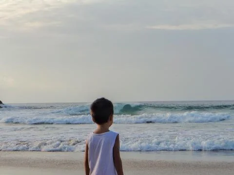 Child on the beach looking at the waves Stock Photos