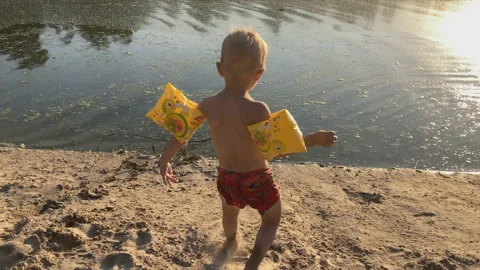 Child in the beautiful light of the sunset, sand to the muddy river Stock Footage 157309491