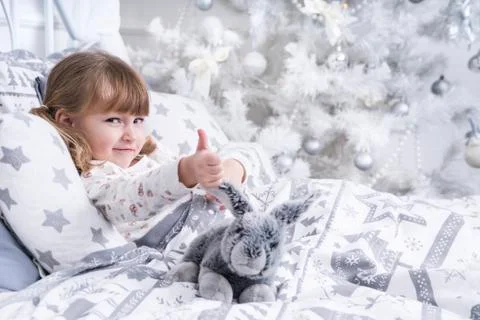 Child in bed with thumb up Stock Photos