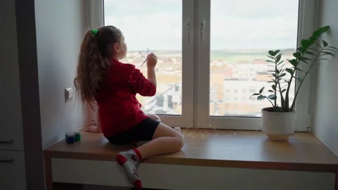 Child begin draw snowflake on window with paint. Female person using paints Stock Footage 166146128