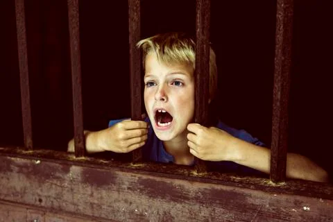 Child behind bars, screaming for help Stock Photos