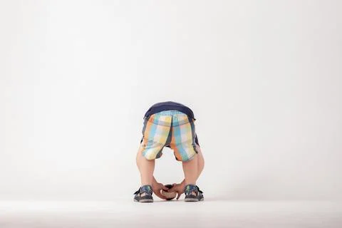 Child bending down in a studio setting looking at the ground with short Stock Photos