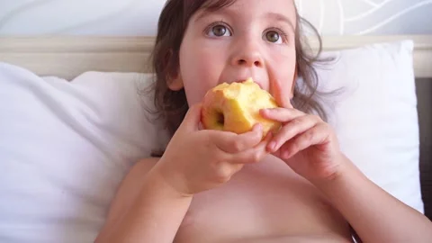 A child bites an apple. Close-up of the face of a child who eats fruit. Video stock 162551034
