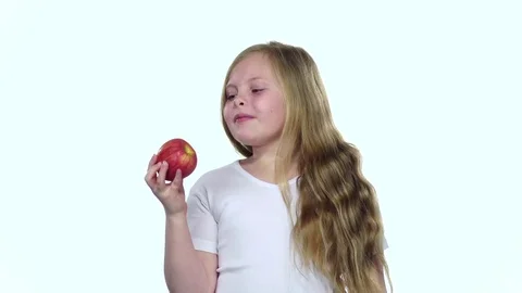 Child bites an apple it is very tasty. White background. Slow motion Vidéo 75789317