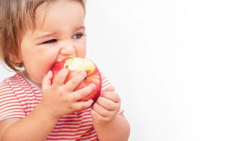 Child bites off apple Stock Photos
