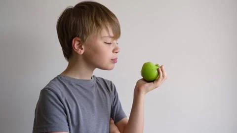 Child bites green apple, isolated over white background. Copy space. Stock Footage 190343247