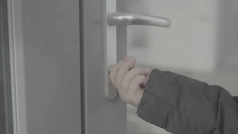 A child in a black jacket opens the handle of a glass door with key. Slog-3 Stock Footage 307490755