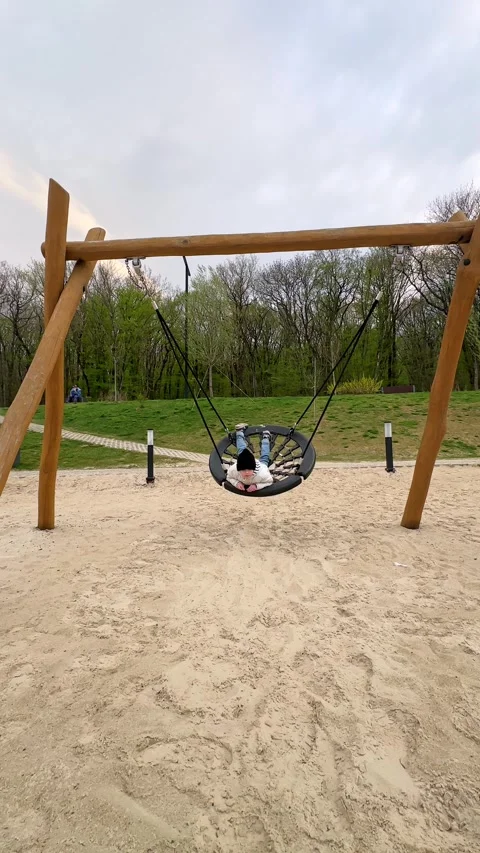 Child in a black round swing at a playground Stock Footage 340652470