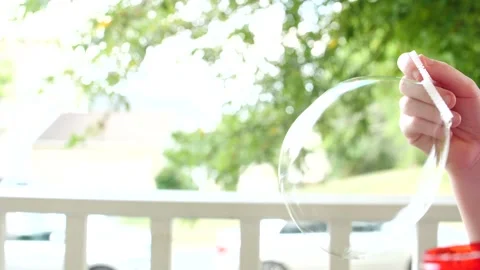 Child blowing giant bubble outside having fun Video stock 207339347