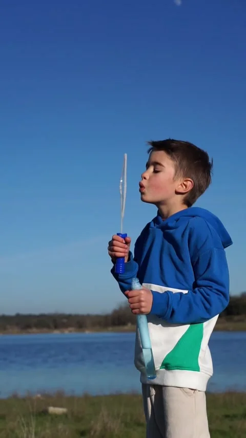 Child blowing soap bubbles in nature with copy space Stock Footage 262425688
