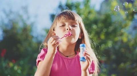 Child is blowing soap bubbles in sunny green outdoors. Slow Motion 240 fps. Stock Footage 55704464