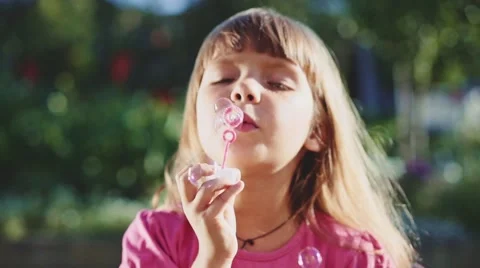 Child is blowing soap bubbles in sunny green outdoors. Slow Motion 240 fps. Vidéo 55704546