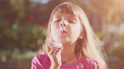 Child is blowing soap bubbles in sunny green outdoors. Slow Motion 240 fps. Vídeos de archivo 55704550