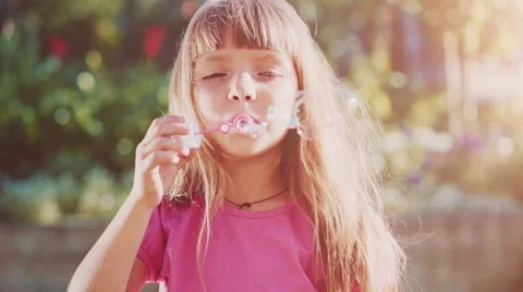 Child is blowing soap bubbles in sunny green outdoors. Slow Motion 240 fps. Vidéo 55704598