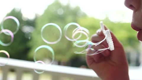 Child blowing a stream of bubbles close up having fun bubbles everywhere Stock Footage 207340031