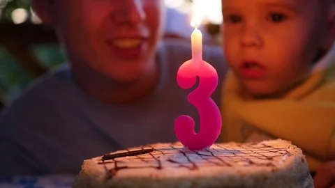 The child blows out the candle on the cake in his birthday with father 库存影片 79571780