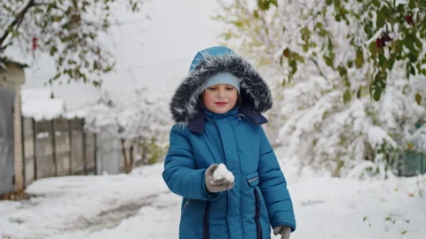 Child in blue winter jacket eating snow. Winter and childhood concept for design Stock Footage 291301047