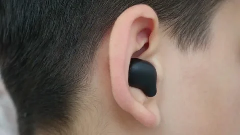 A child with a bluetooth headset in his ear listens to music, Stock Footage 157913952