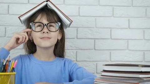 A child with a book on head thinks. Stock Footage 103225989