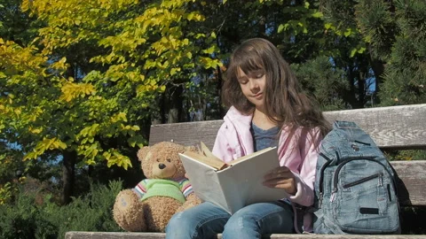 A child with a book in the park. Vídeos de archivo 107281066