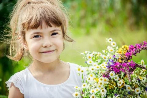 Child with a bouquet of wildflowers. Selective focus. Stock Photos