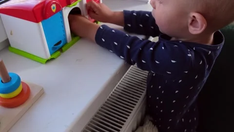 Child boy 1 or 2 years old plays with garage toys and cars on the window at home Stock Footage 275149058