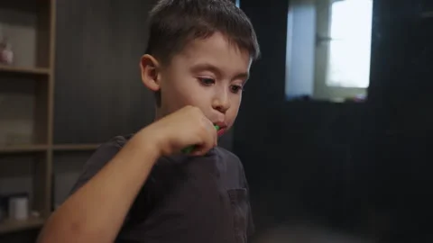 Child boy brushing his teeth with a toothbrush and looking into the frame Stock Footage 249791989