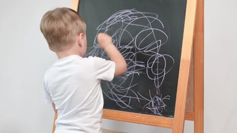Child boy draws scrawl with chalk on a blackboard close-up. Stock Footage 240527121