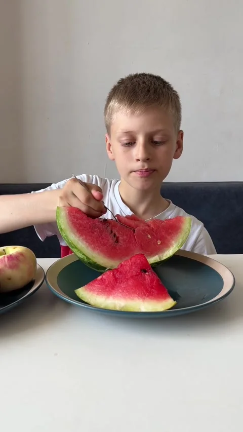 Child boy eating watermelon from plate with spoon, fresh summer fruit and Stock Footage 337362891
