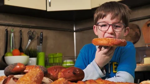 Child boy eats bread bun in the kitchen Stock Footage 134223820