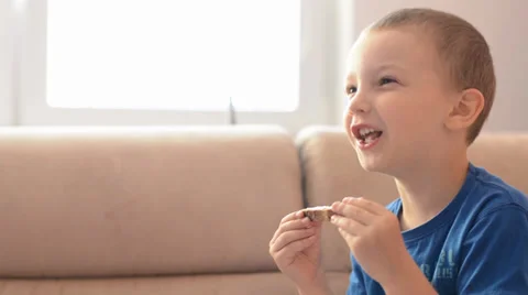 Child (boy) eats bread with butter, watchs TV and he laughs Vídeo Stock 39479323