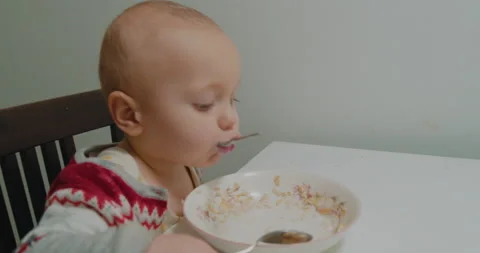 Child boy eats children's healthy food in a chair for children at home. Stock Footage 229034429