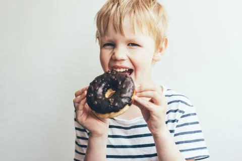 A child boy eats a chocolate donut Stock Photos