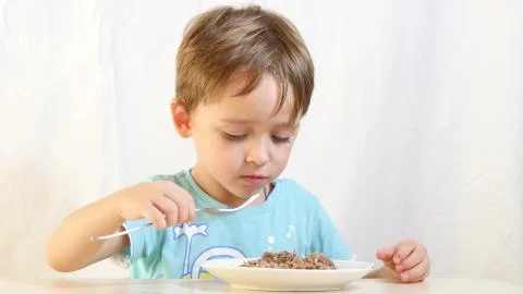 Child boy eats food with a fork from a plate. Stock Photos