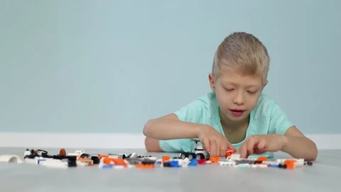 A child boy enthusiastically collects a constructor on the floor from small Stock Footage 160814803