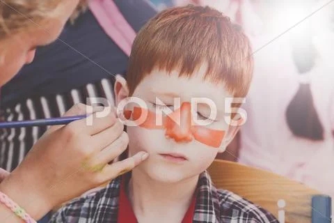 Child boy face painting, making tiger eyes process Stock Photos