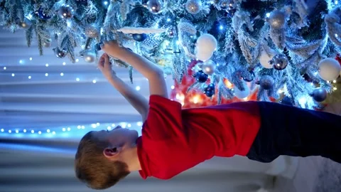A child boy hangs New Year's decorations on a Christmas tree Stock Footage 258357655