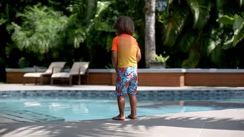 Child boy jumping into pool on a hot summer day during quarantine staycation Stock Footage 136492871