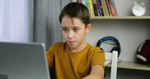 Child boy looks at laptop screen with focus. Concept shows parental control and Stock Footage 329487282