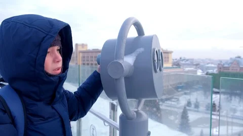 Child boy looks through binoculars on roof of building in city in winter. Stock Footage 117618765