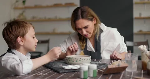 Child boy with mother making pattern on clay bowl. Kid and mom spend time Video stock 156384912