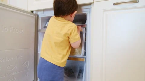 Child boy opening freezer compartment in kitchen. Little toddler looking inside Stock Footage 343169540